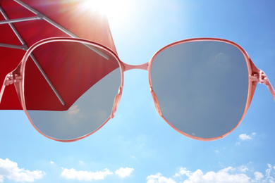 Image of Red umbrella and blue sky on sunny day, view through sunglasses