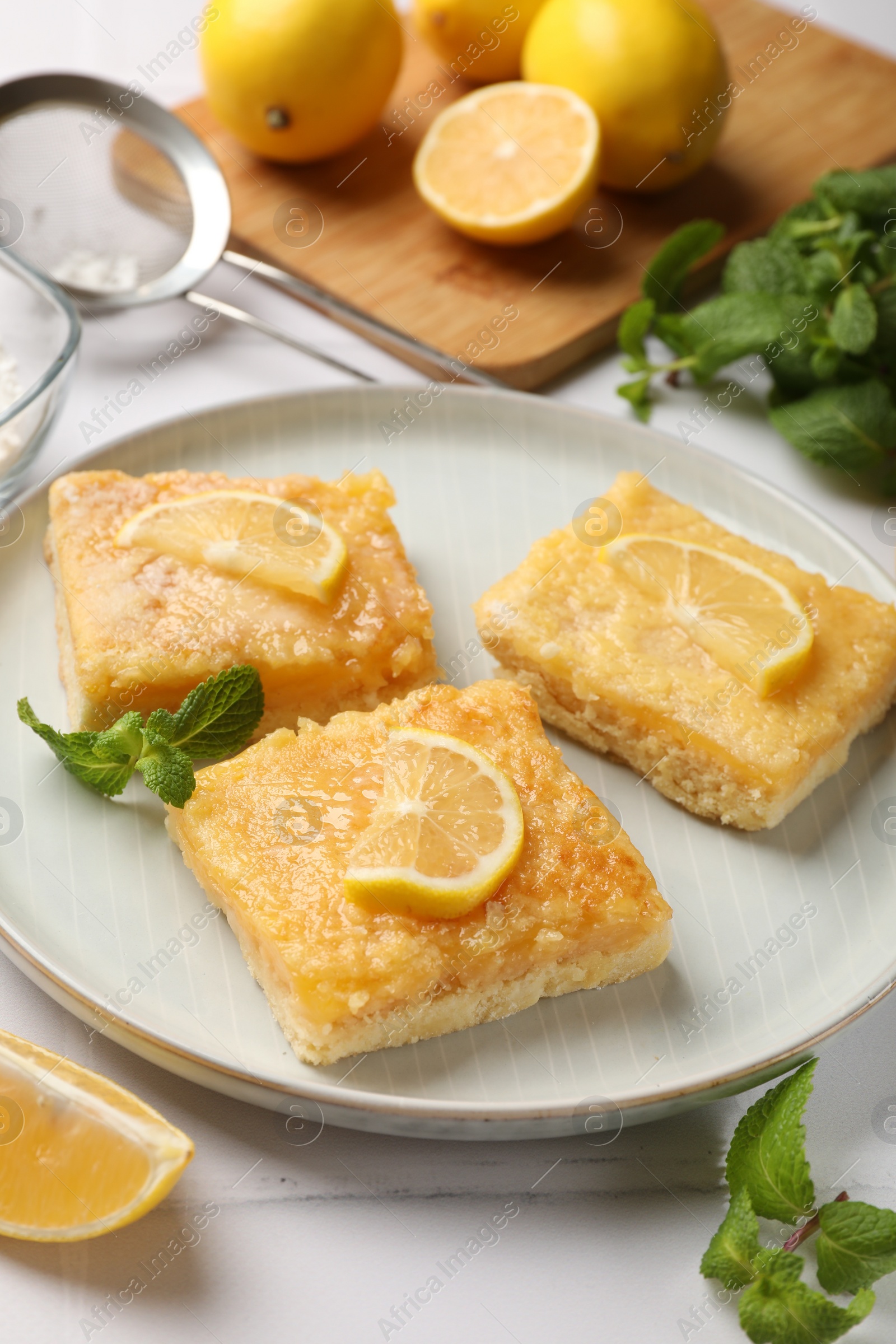 Photo of Tasty lemon bars and mint on white table