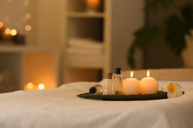 Photo of Cosmetics and burning candles on massage table in spa salon, space for text