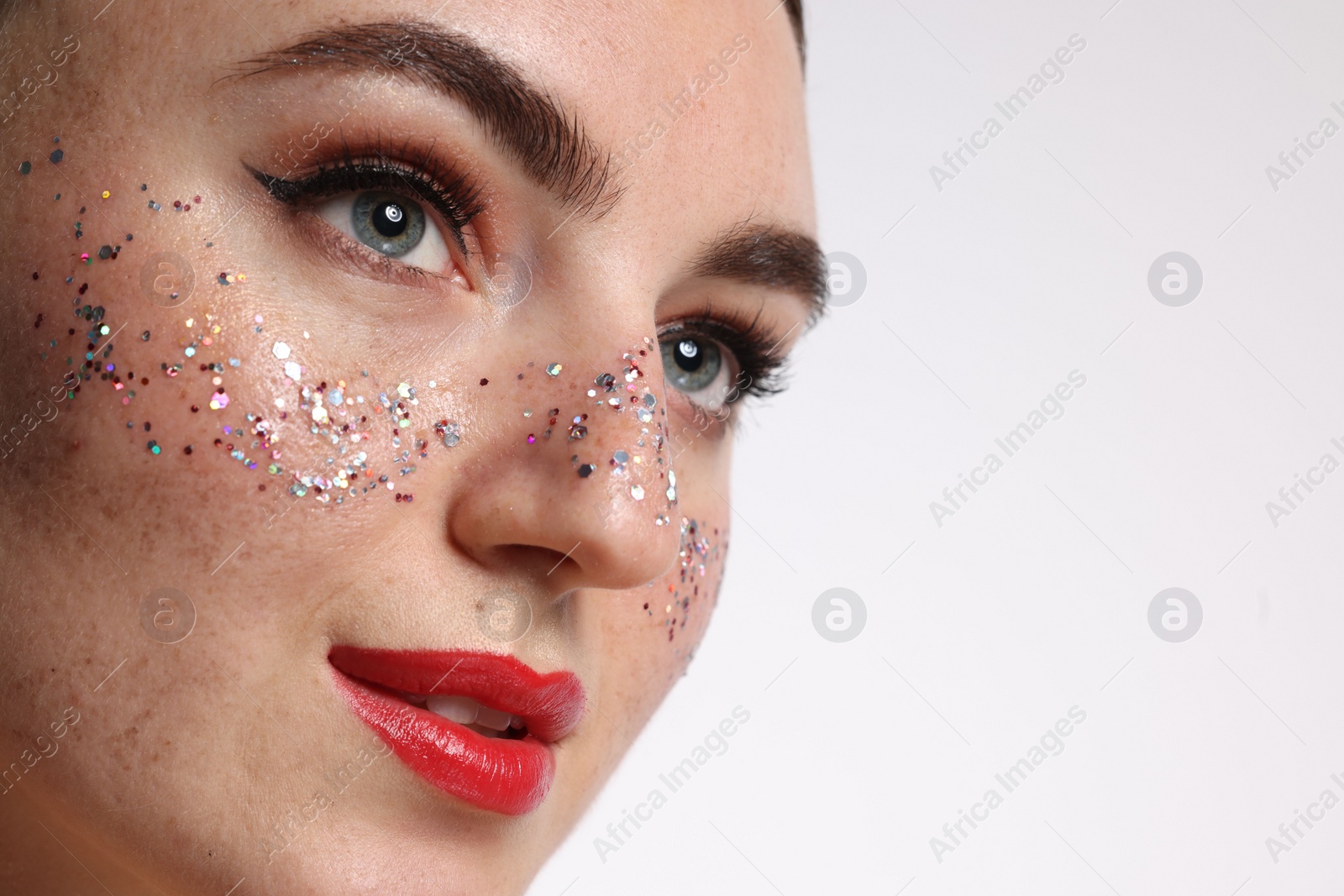 Photo of Beautiful woman with glitter freckles on white background, closeup. Space for text