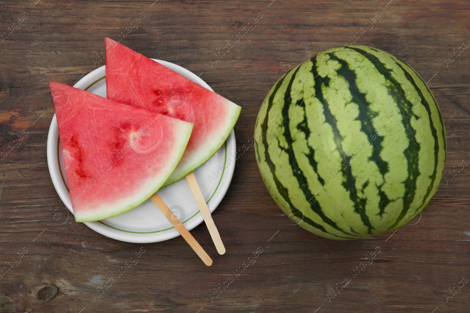 Photo of Whole and sliced delicious ripe watermelons on wooden table, flat lay
