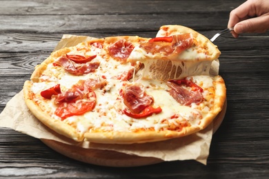 Woman holding shovel with slice of delicious hot pizza over table, closeup