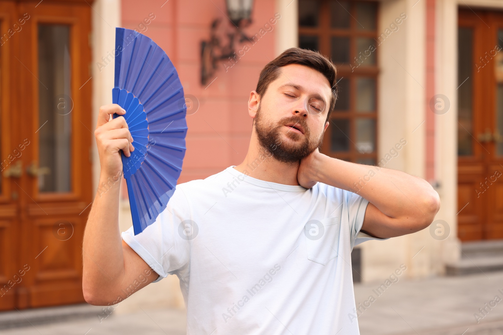 Photo of Man with hand fan suffering from heat outdoors