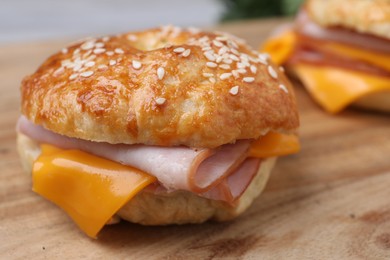 Photo of Delicious bagels with ham and cheese on wooden table, closeup