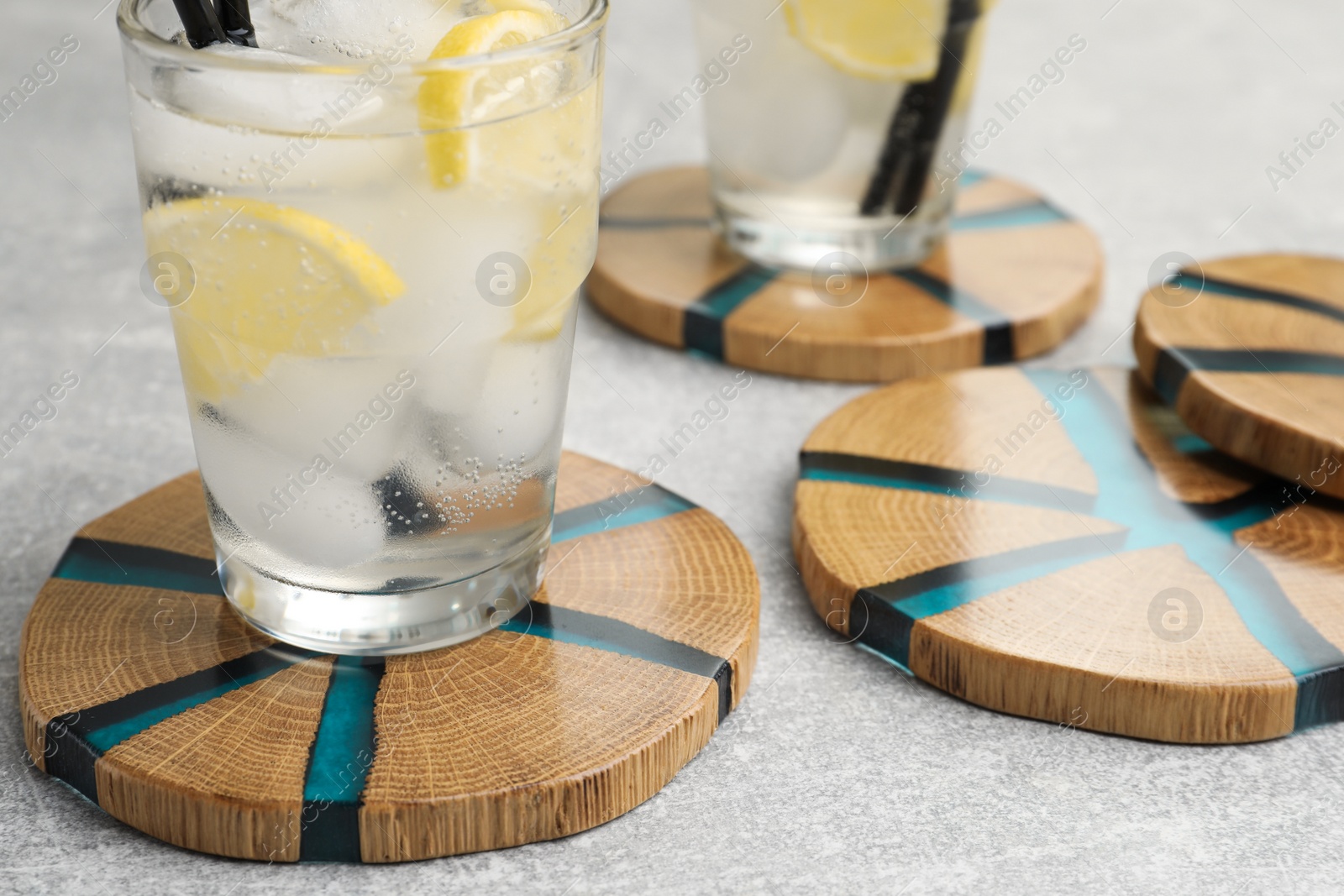 Photo of Cocktail and stylish cup wooden coasters on light grey table