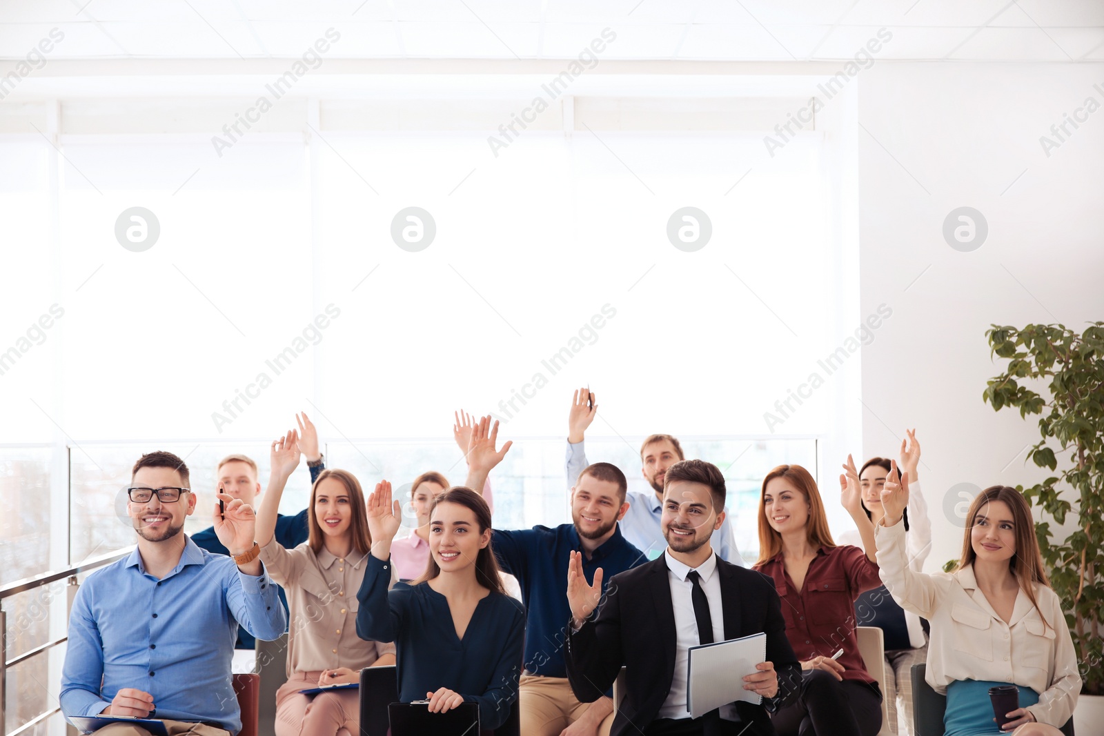 Photo of People raising hands to ask questions at business training indoors