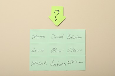 Photo of Choosing baby`s name. Paper stickers with different names and question mark on beige background, flat lay