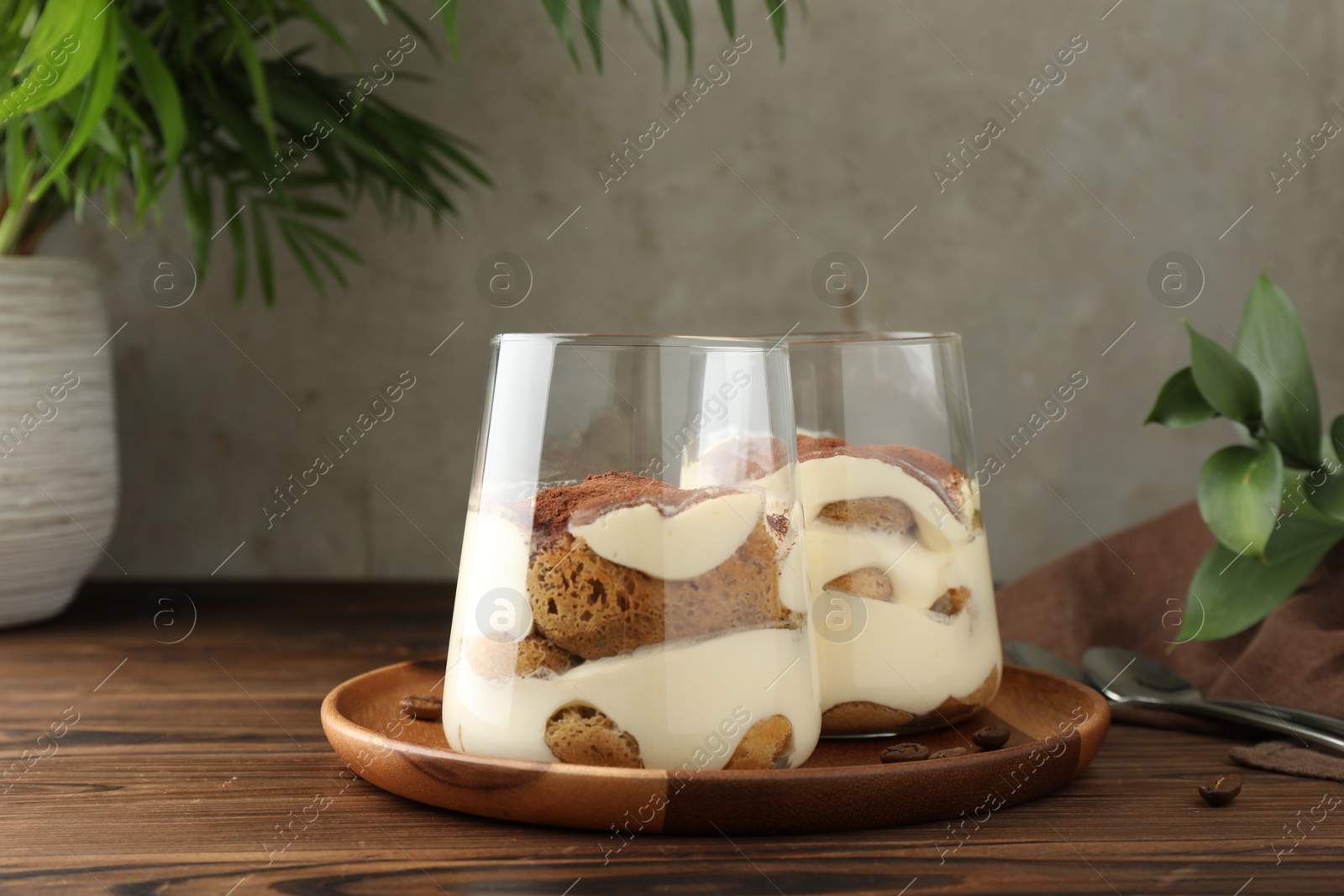 Photo of Delicious tiramisu in glasses on wooden table