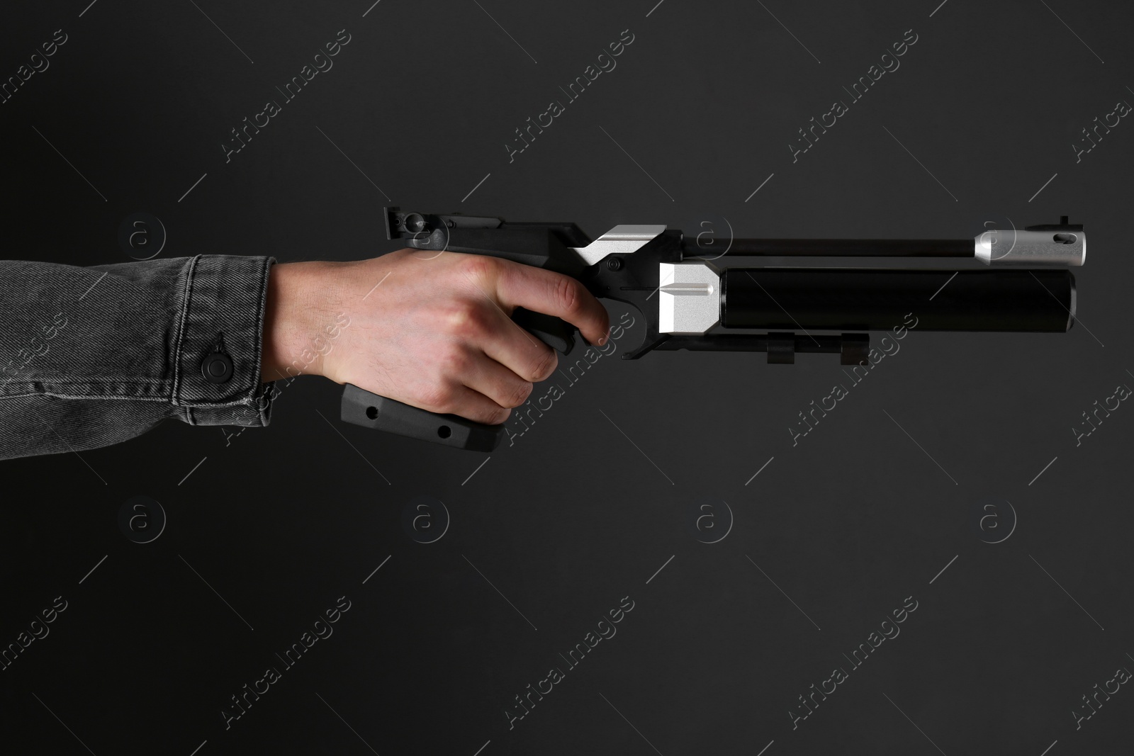 Photo of Gun shooting sport. Man aiming standard pistol on dark background, closeup