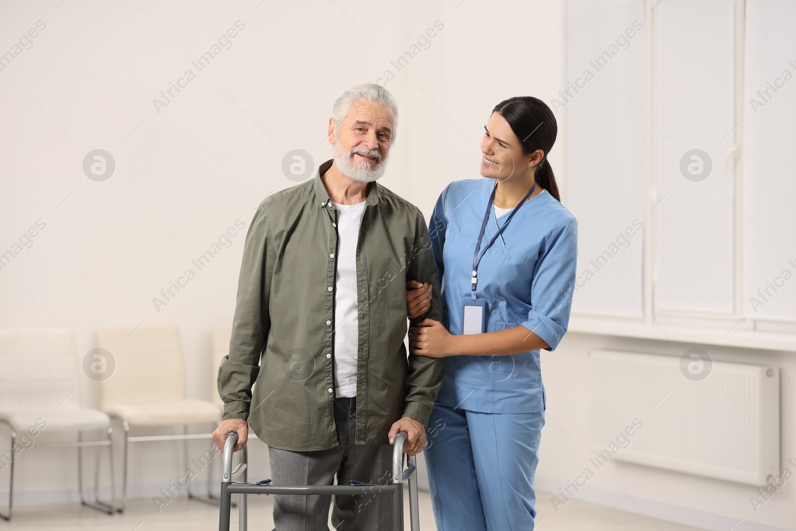 Photo of Smiling nurse supporting elderly patient in hospital