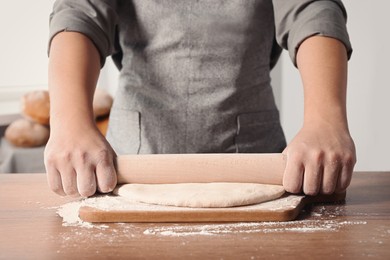 Photo of Man rolling dough at table in kitchen, closeup