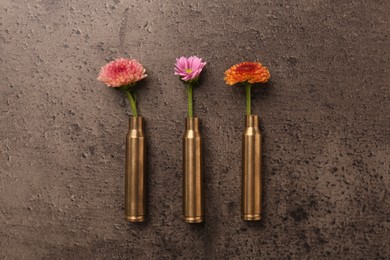 Photo of Beautiful flowers in bullet cases on grey textured table, flat lay