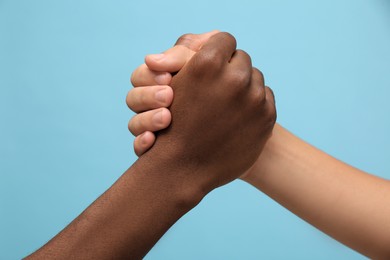 Photo of Men clasping hands on light blue background, closeup