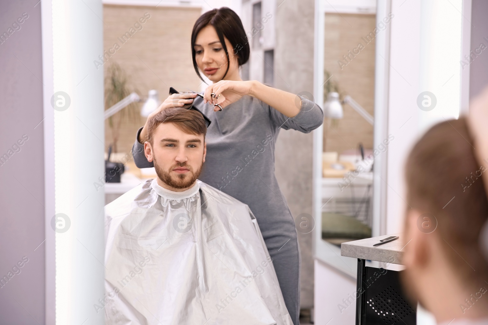 Photo of Professional female hairdresser working with client in salon