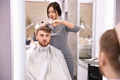 Professional female hairdresser working with client in salon