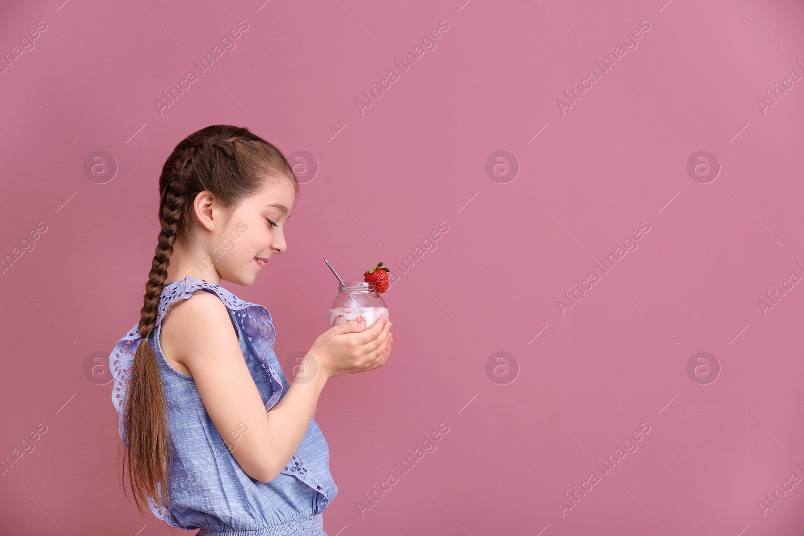 Photo of Cute girl eating tasty yogurt on color background