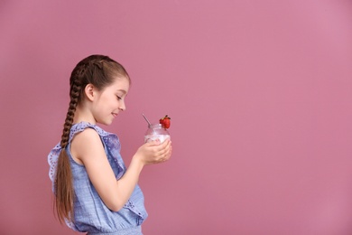 Cute girl eating tasty yogurt on color background