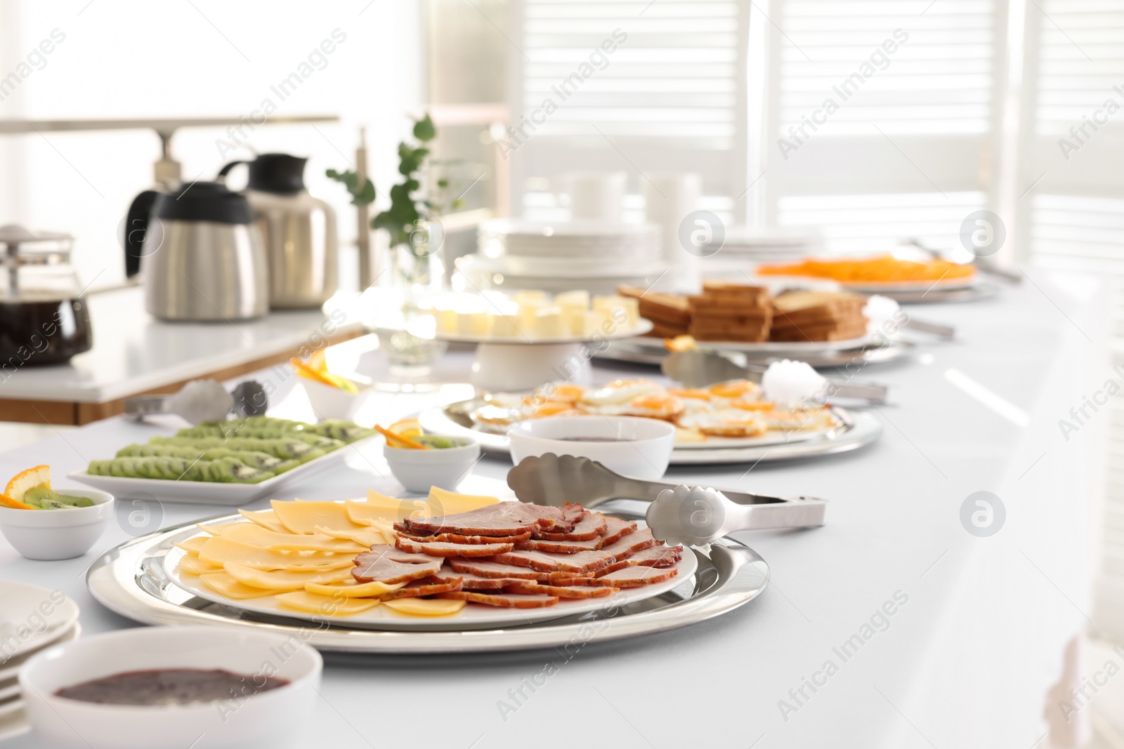 Photo of Different meals for breakfast on white table indoors. Buffet service