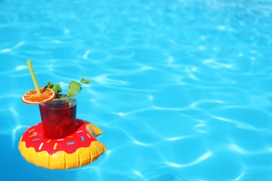 Photo of Inflatable drink holder with cocktail in swimming pool on sunny day. Space for text