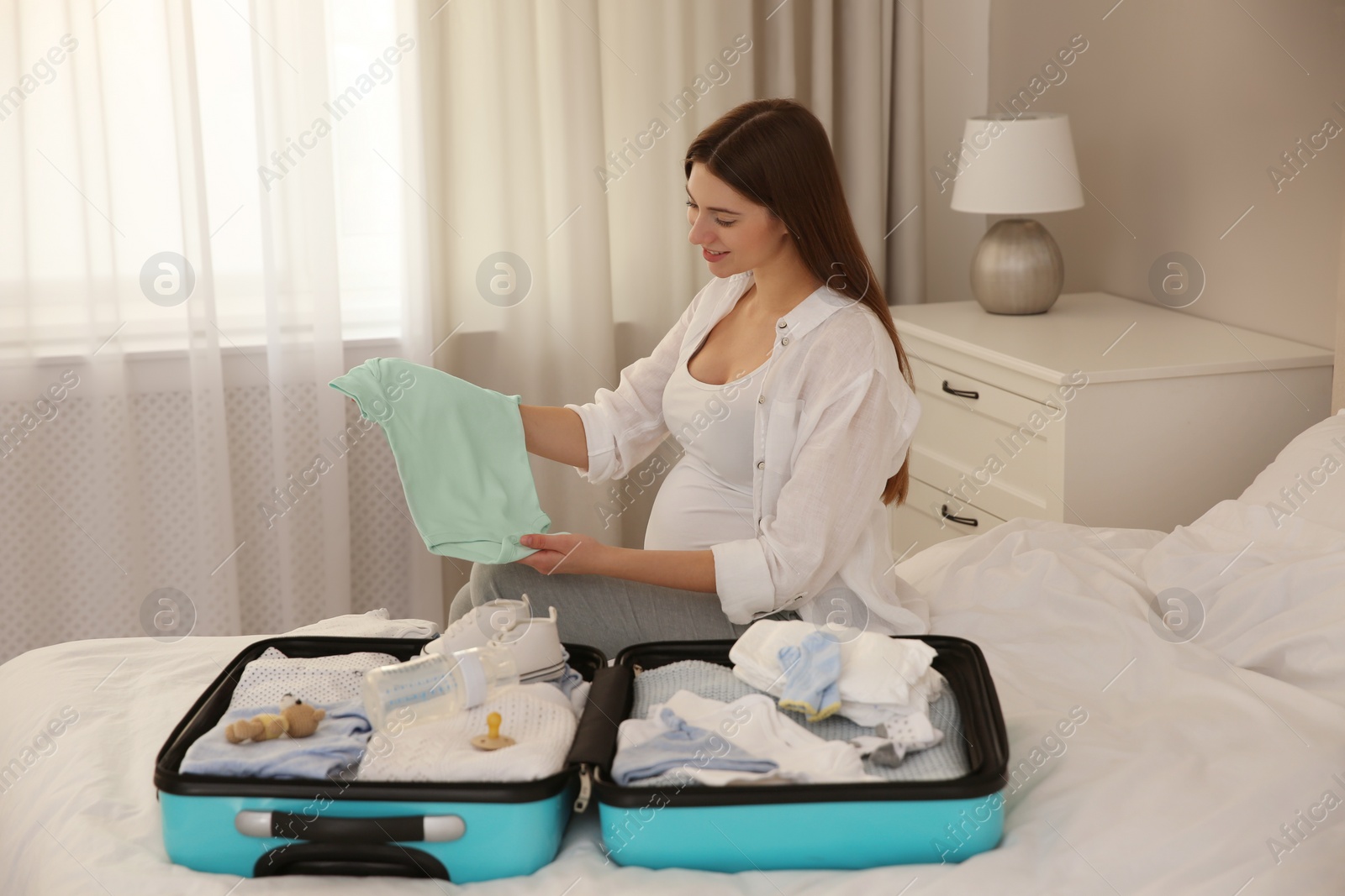 Photo of Pregnant woman packing suitcase for maternity hospital at home