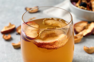 Photo of Delicious compote with dried apple slices in glass on table, closeup