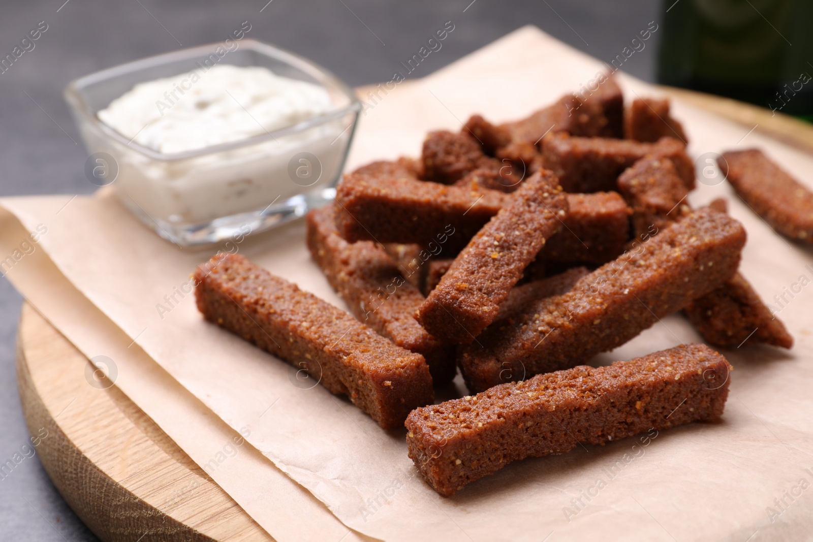 Photo of Crispy rusks and dip sauce on wooden board, closeup