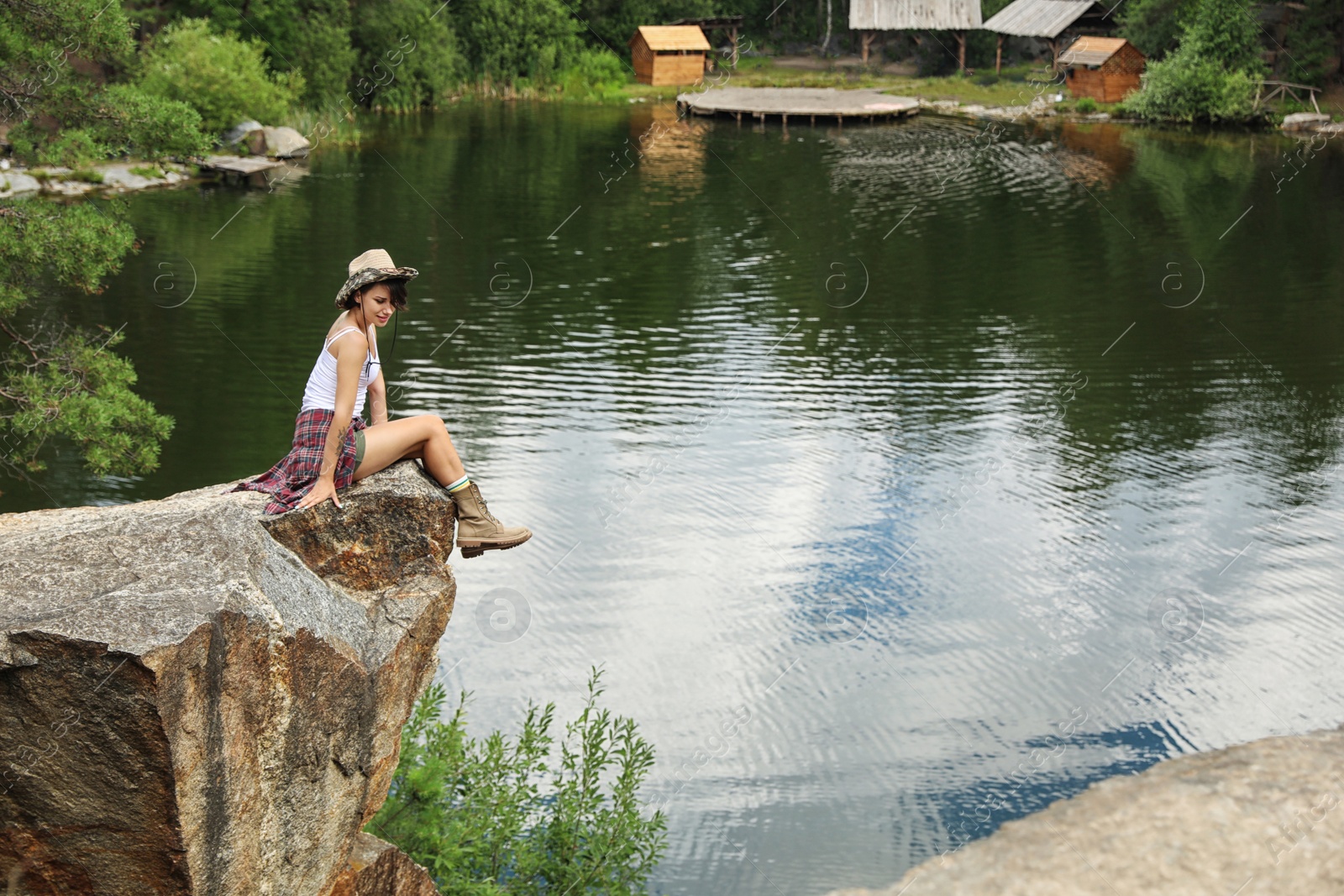 Photo of Young woman on rocky mountain near lake. Camping season