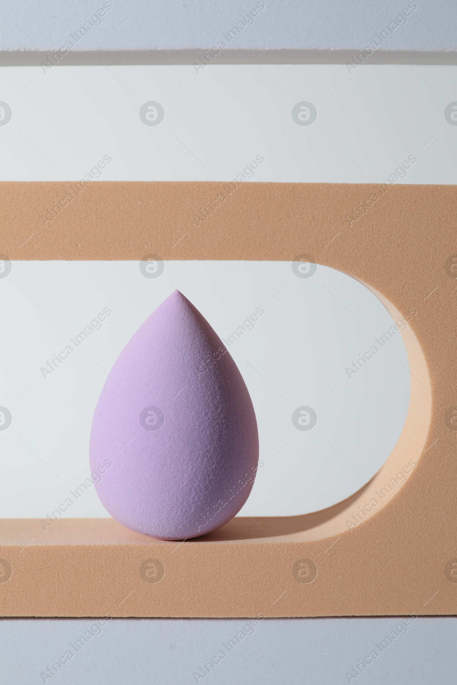 Photo of Stylish presentation of violet makeup sponge on white background