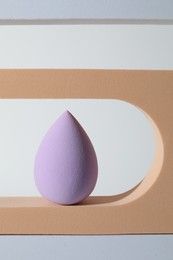 Photo of Stylish presentation of violet makeup sponge on white background