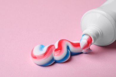 Photo of Tube with squeezed out toothpaste on pink background, closeup
