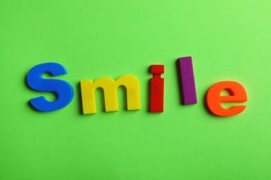 Photo of Word SMILE of magnetic letters on color background, top view