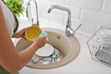 Photo of Woman washing dirty dishes in kitchen sink, closeup. Cleaning chores