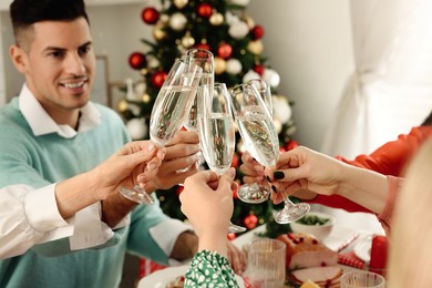 Photo of Family with their friends clinking glasses at festive dinner indoors. Christmas Eve celebration