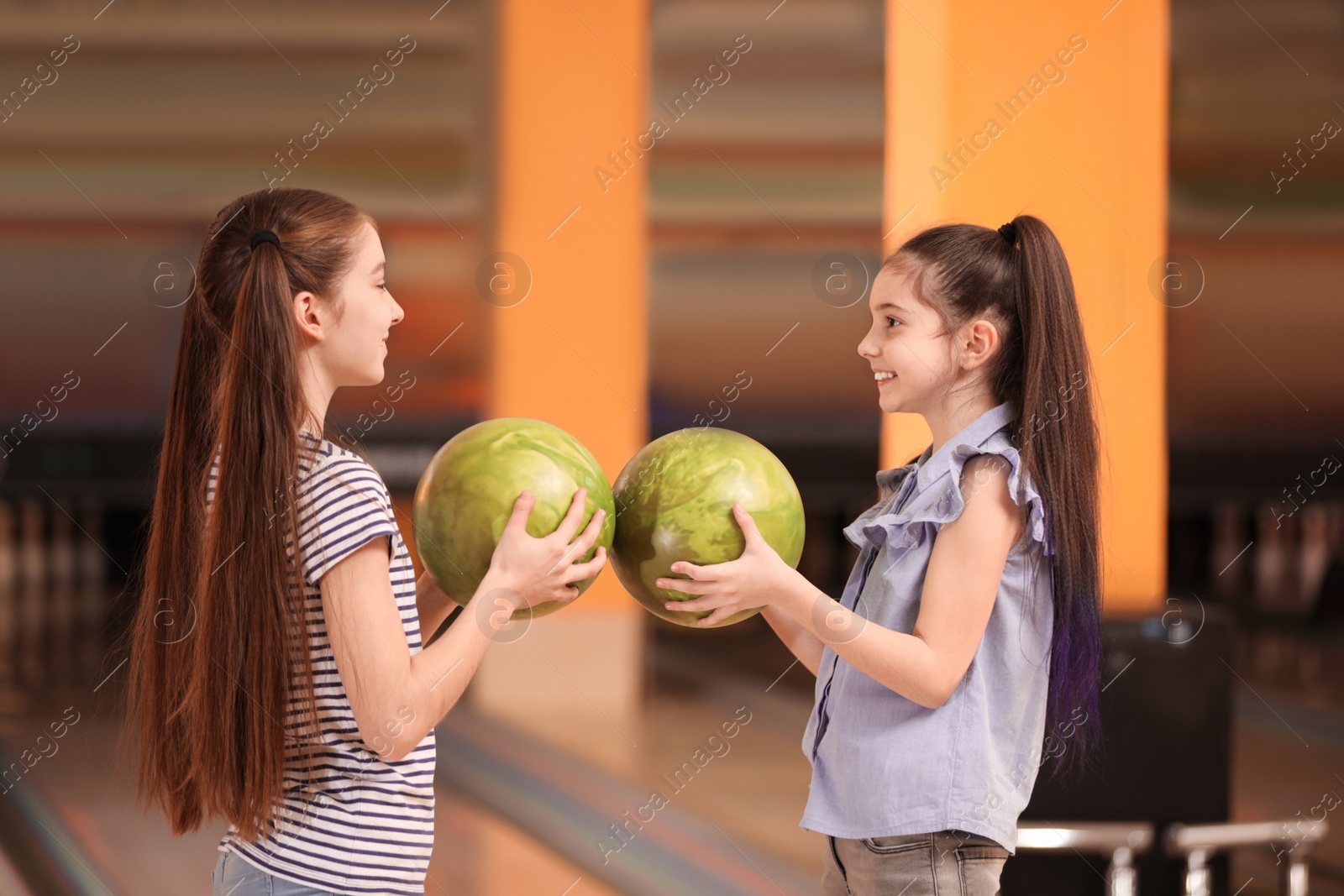 Photo of Happy girls with balls in bowling club