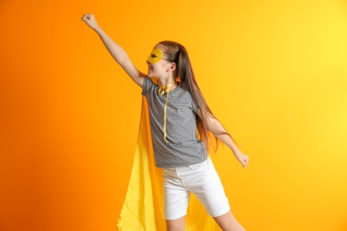 Photo of Adorable little child playing superhero on color background. Indoor recreation