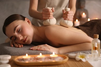 Photo of Spa therapy. Beautiful young woman lying on table during herbal bag massage in salon