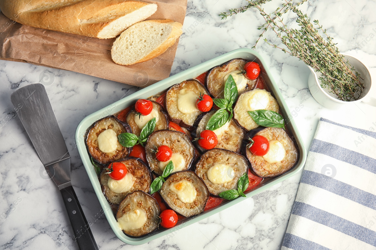 Photo of Flat lay composition with baked eggplant, tomatoes and basil in dishware  on marble table