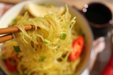 Photo of Stir-fry. Eating tasty noodles with chopsticks at table, closeup and space for text