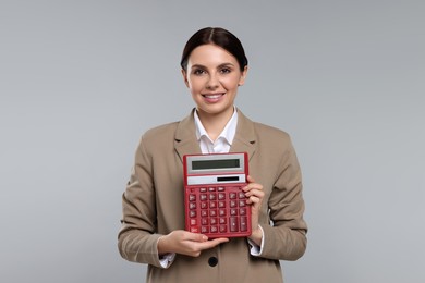 Smiling accountant with calculator on grey background