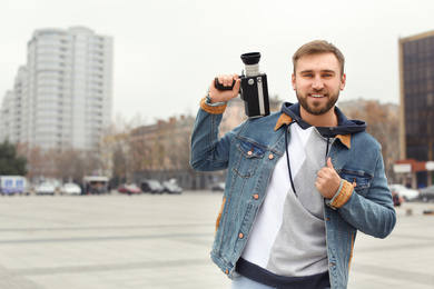 Photo of Young man with vintage video camera on city street