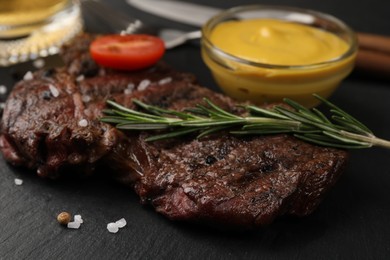 Photo of Delicious fried steak with rosemary and sauce on black table, closeup