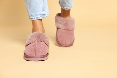 Woman in warm soft slippers on beige background, closeup. Space for text