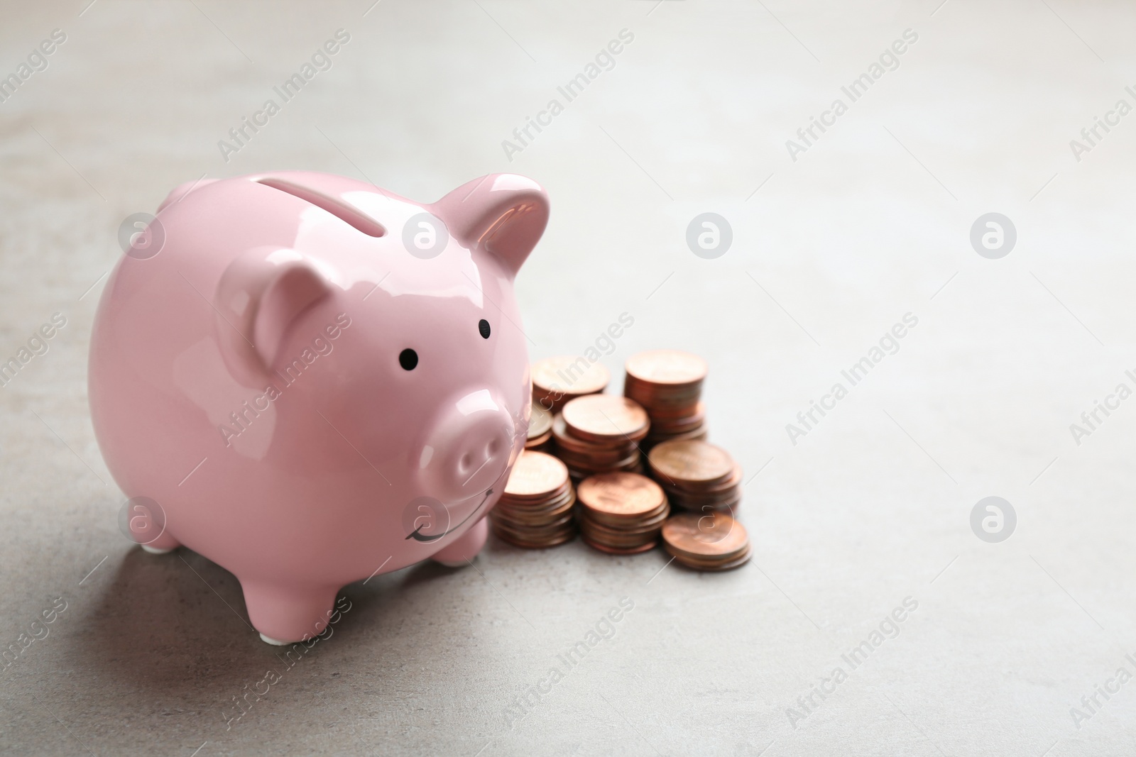 Photo of Piggy bank and coins on grey background. Space for text