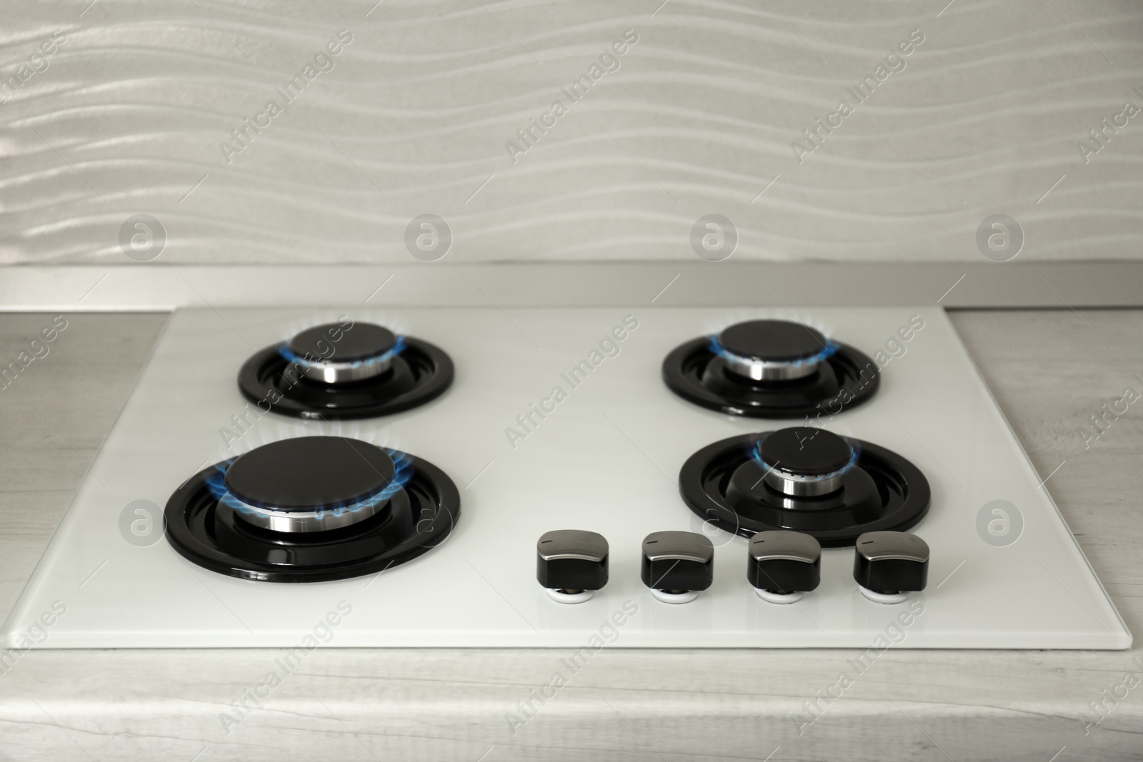 Photo of Gas burners with blue flame on modern stove