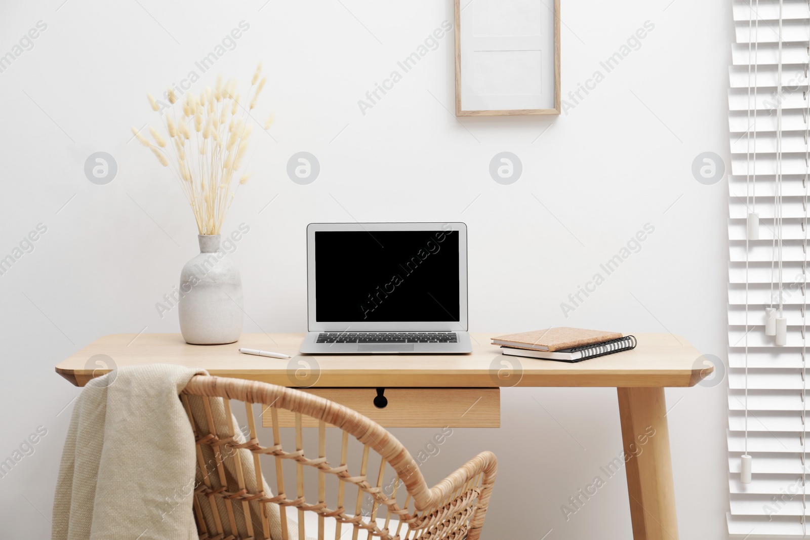 Photo of Cozy workspace with modern laptop on desk and comfortable chair at home