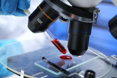 Photo of Laboratory worker running blood test using microscope, closeup. Research and analysis