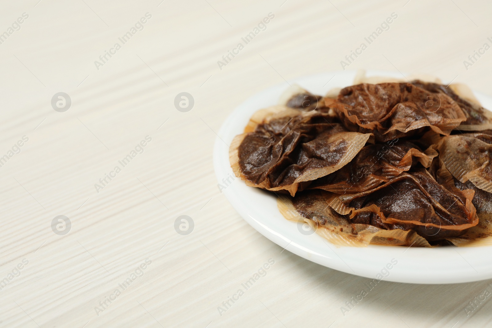 Photo of Used tea bags on white wooden table. Space for text