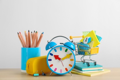 Photo of Different school stationery and alarm clock on table against white background. Back to school