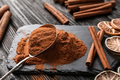 Aromatic cinnamon powder and sticks on wooden background