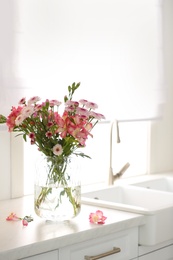 Photo of Vase with beautiful flowers on kitchen counter. Stylish element of interior design
